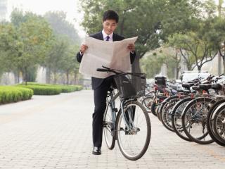 Man on bike reading a newspaper